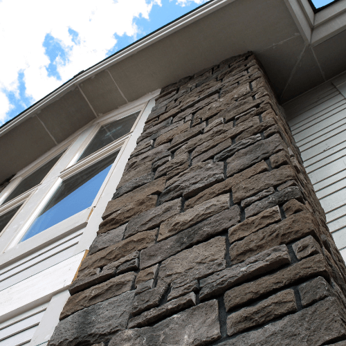 Picture of a close up of stone siding vertical strip on a white sided house